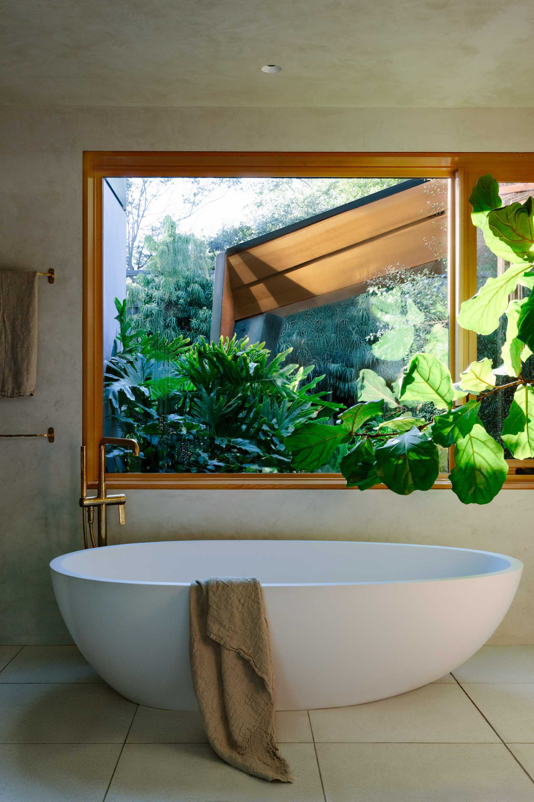 A bathroom with a freestanding bathtub and wood window frames.