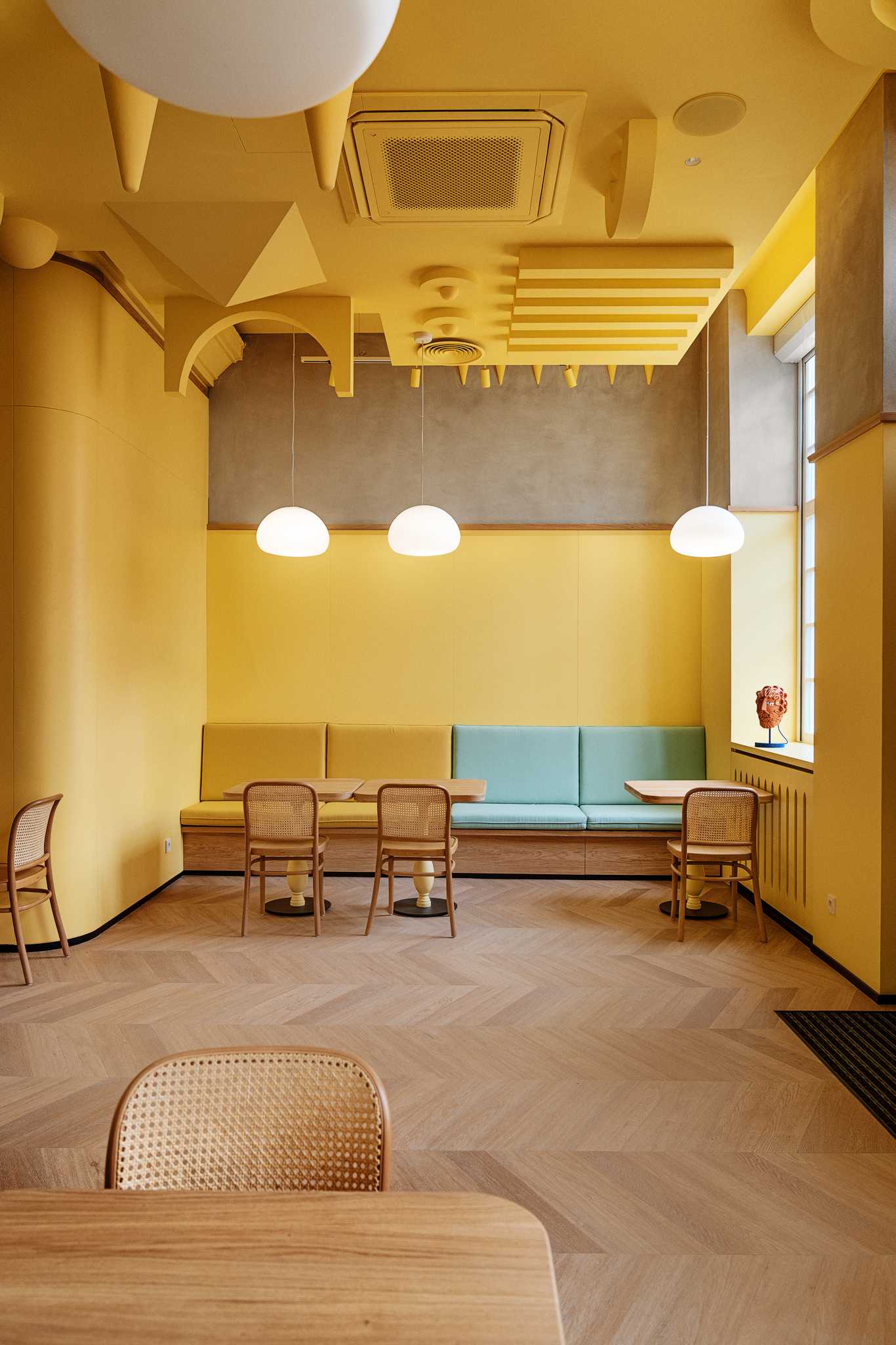 A modern dessert cafe with a bright yellow interior and sculptural ceiling.