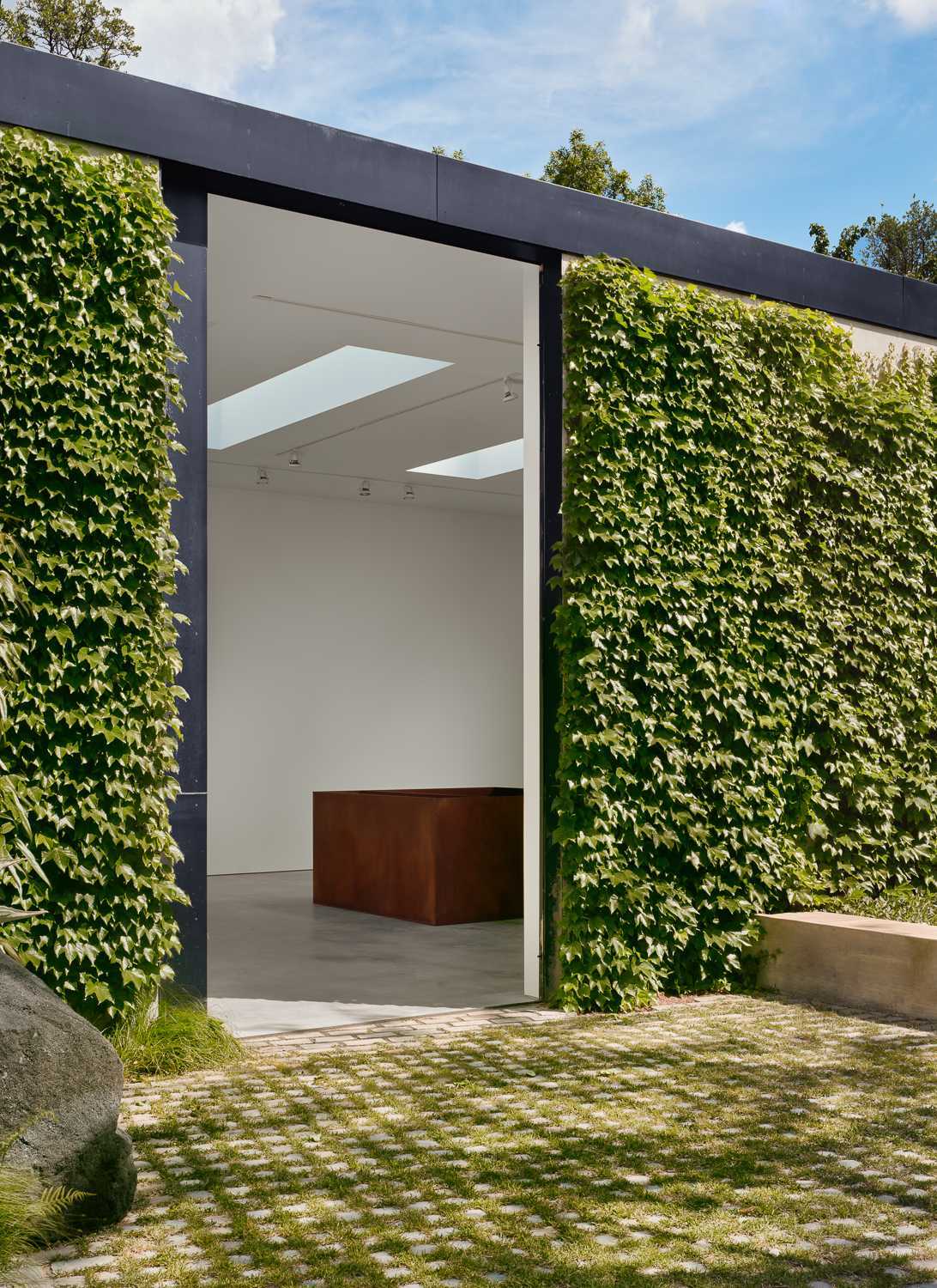 A modern home has a separate, single-story, ivy-covered structure houses the gallery and gallery office, as well as a pool cabana and guest suite.