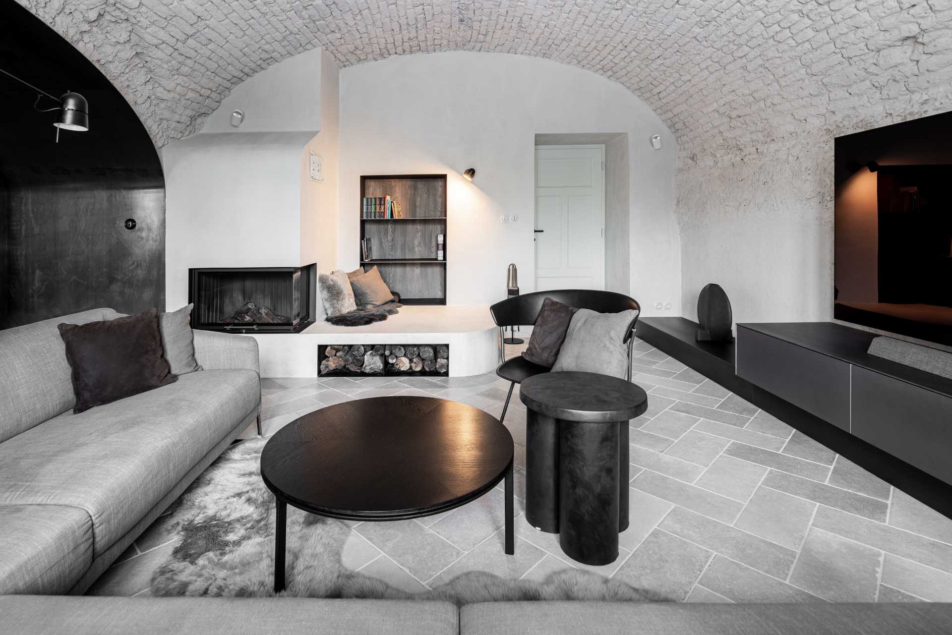 This modern living room in a renovated medieval guard house includes a fireplace with a seating area and built-in bookshelves.