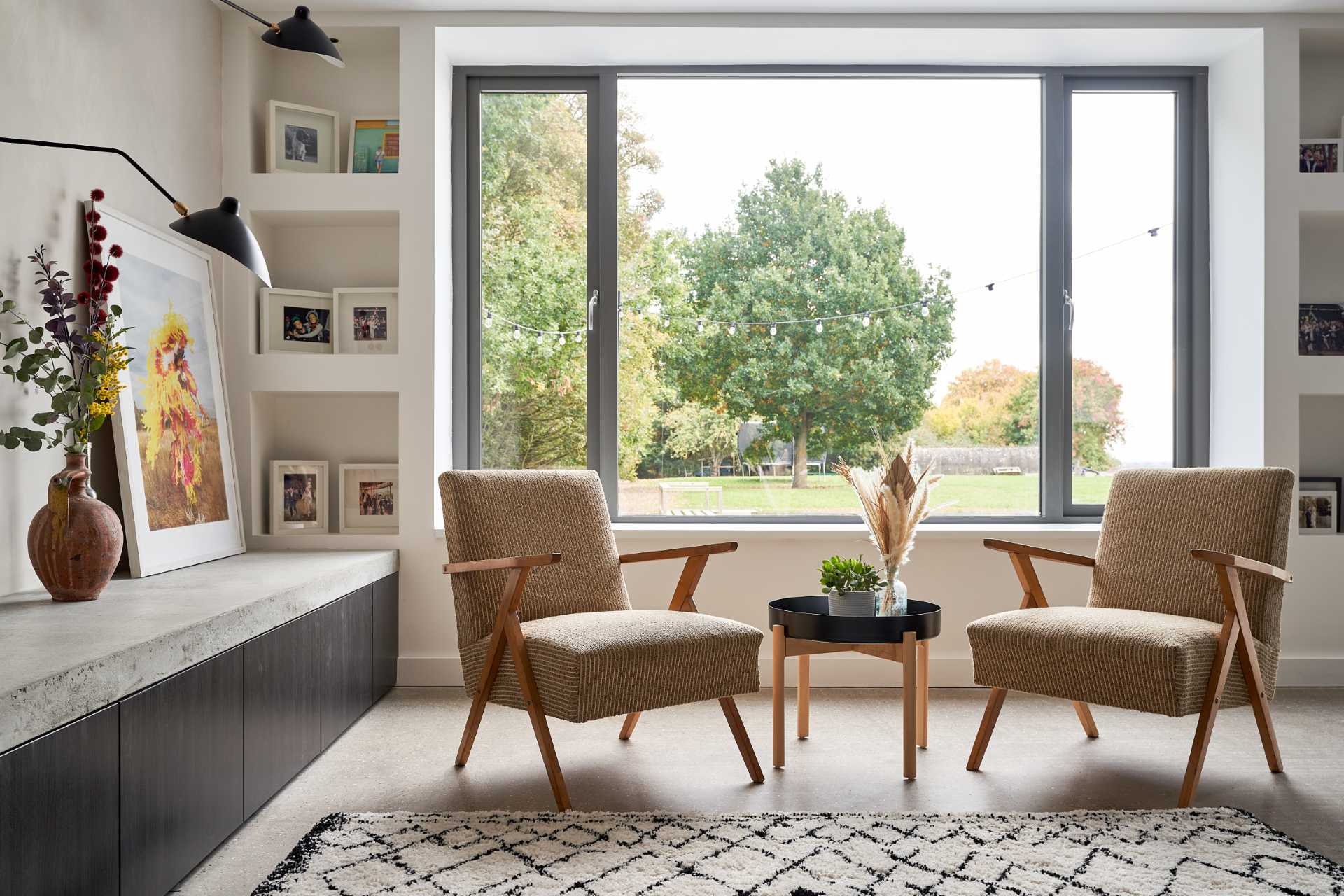 In this living room there's a new fireplace and bench, which can also be used for firewood storage, while a custom wood shelving unit fills a wall, and a black accent wall provides a backdrop for the couch.