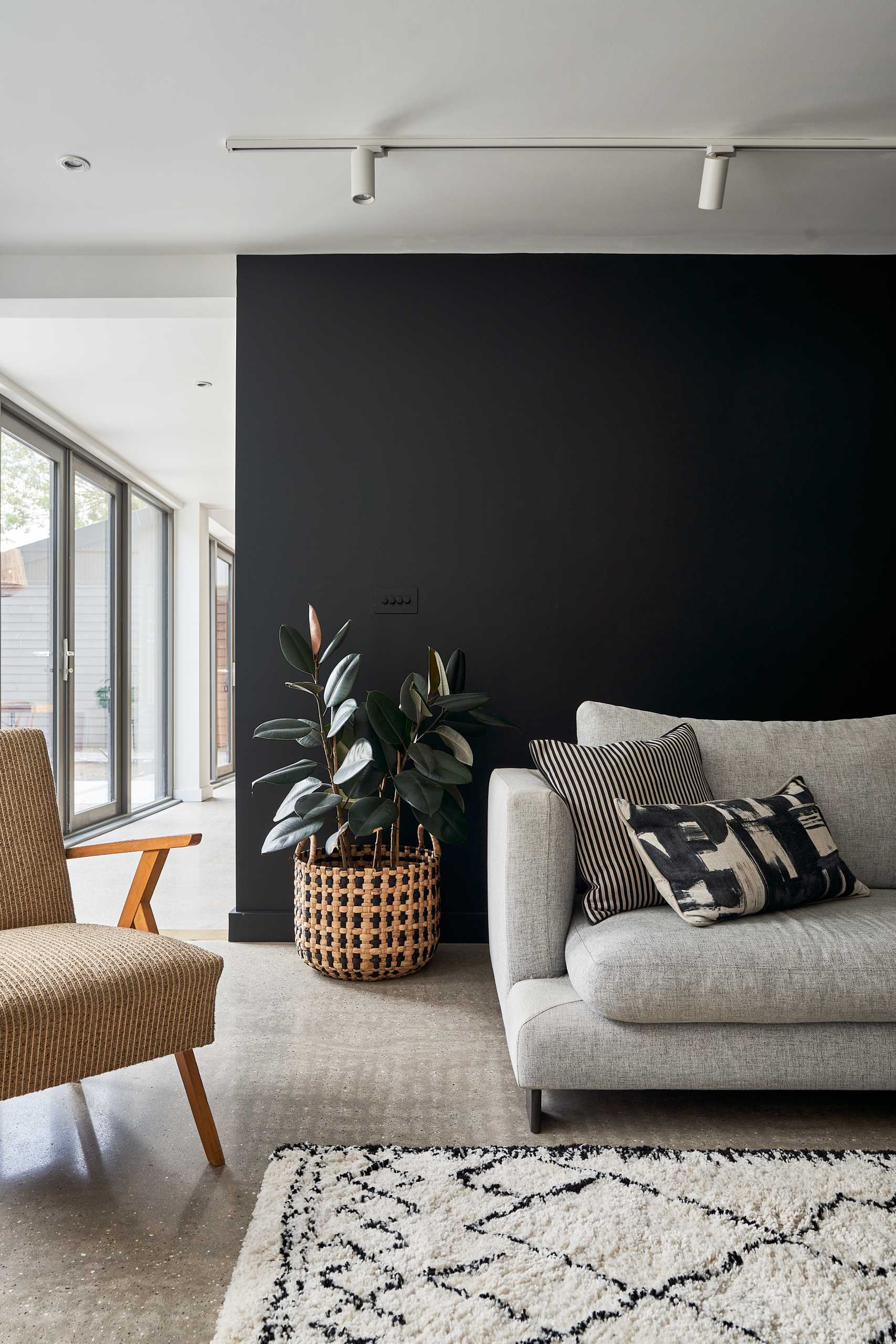 In this living room there's a new fireplace and bench, which can also be used for firewood storage, while a custom wood shelving unit fills a wall, and a black accent wall provides a backdrop for the couch.