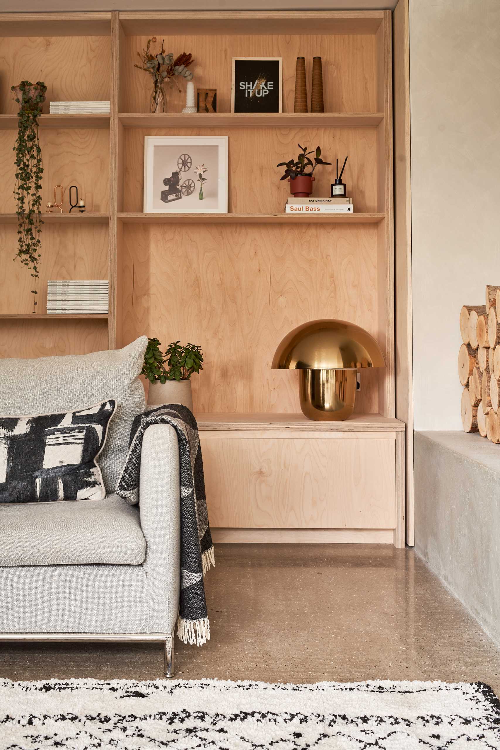 In this living room there's a new fireplace and bench, which can also be used for firewood storage, while a custom wood shelving unit fills a wall, and a black accent wall provides a backdrop for the couch.