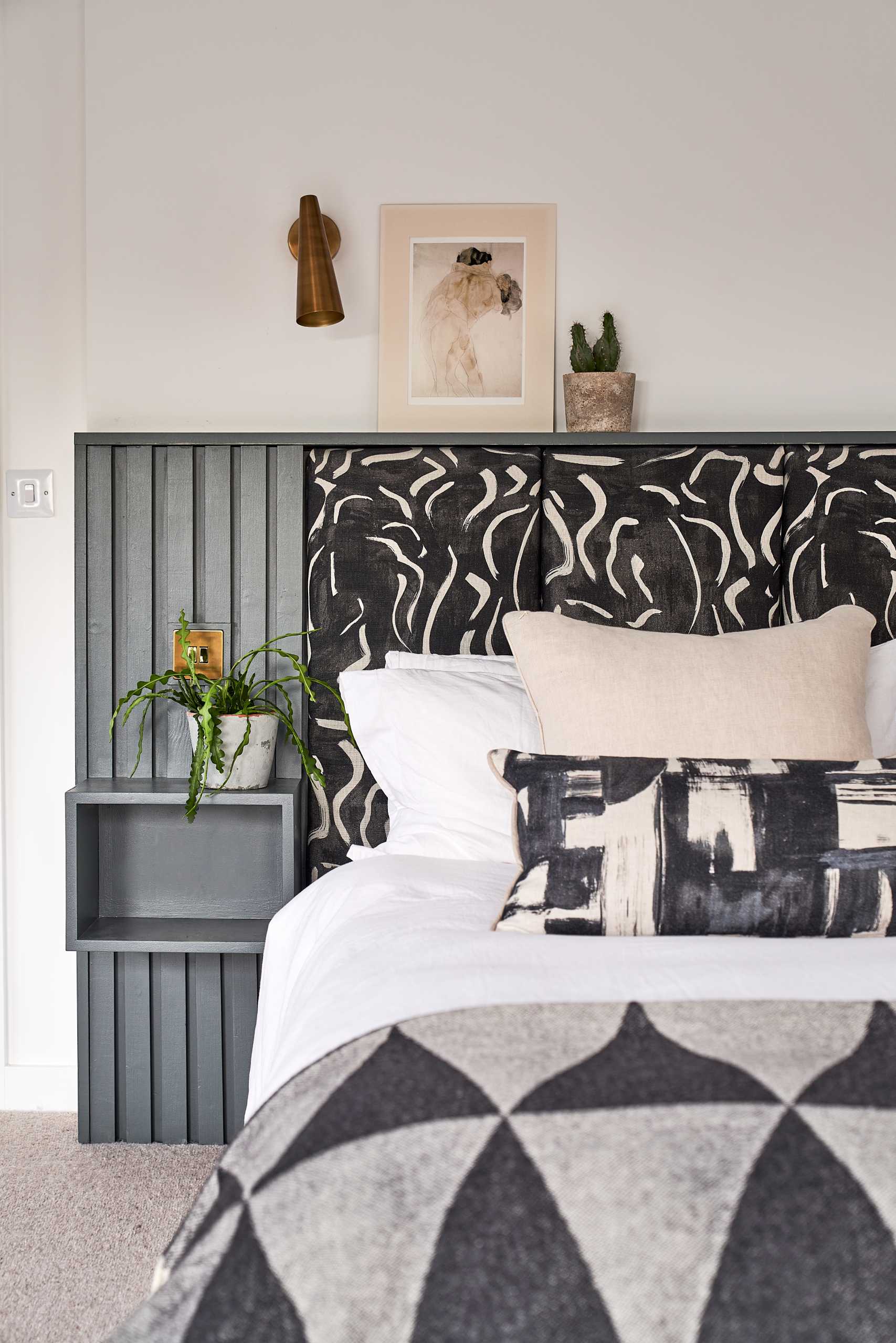 In this primary bedroom, the structural elements of the barn are on display, while the bed headboard incorporates floating bedside tables.