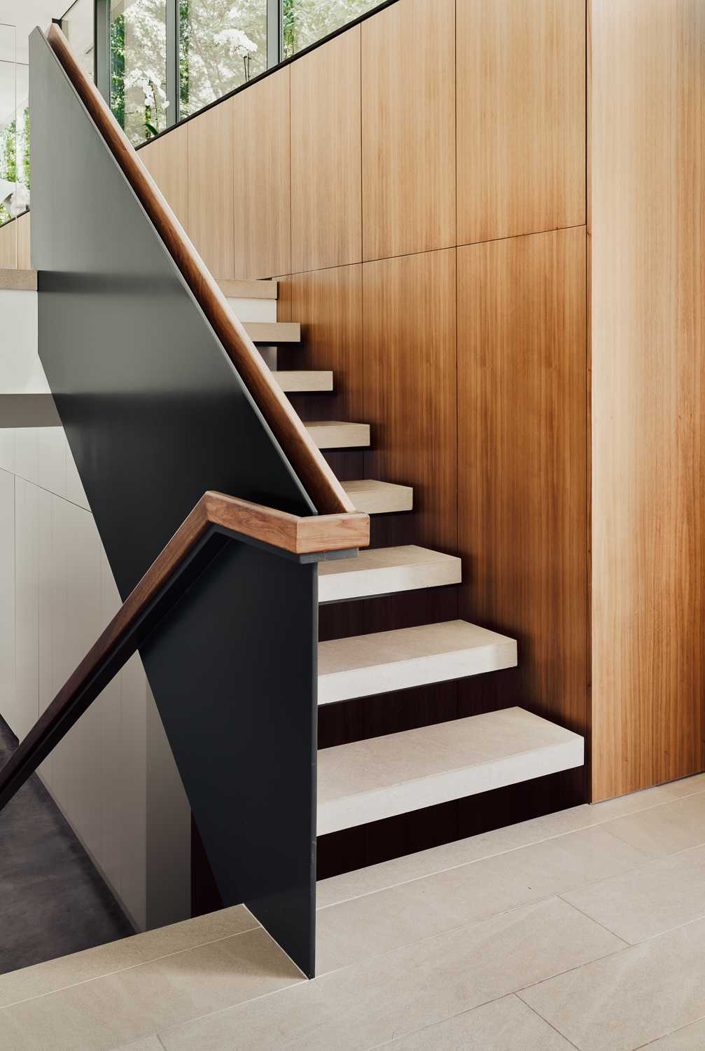 Modern stairs that run alongside a wall of wood panels.