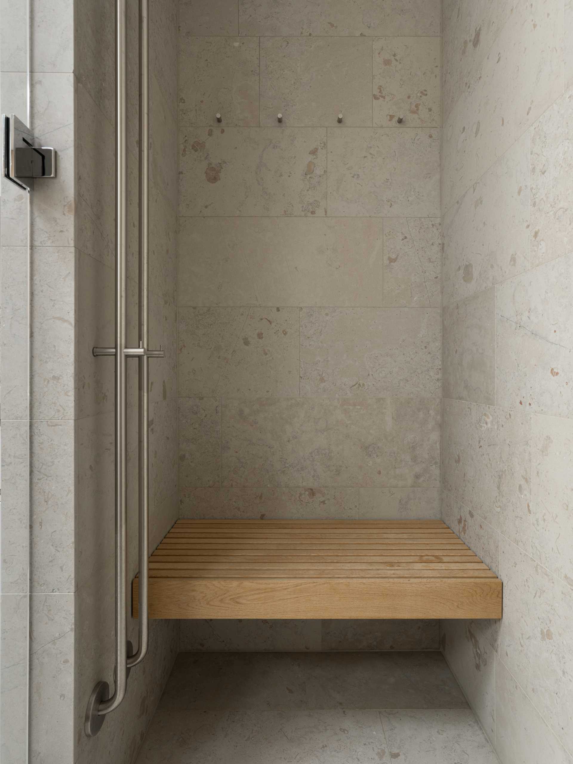 A modern bathroom with a wood bench and tiled covered walls and floors.