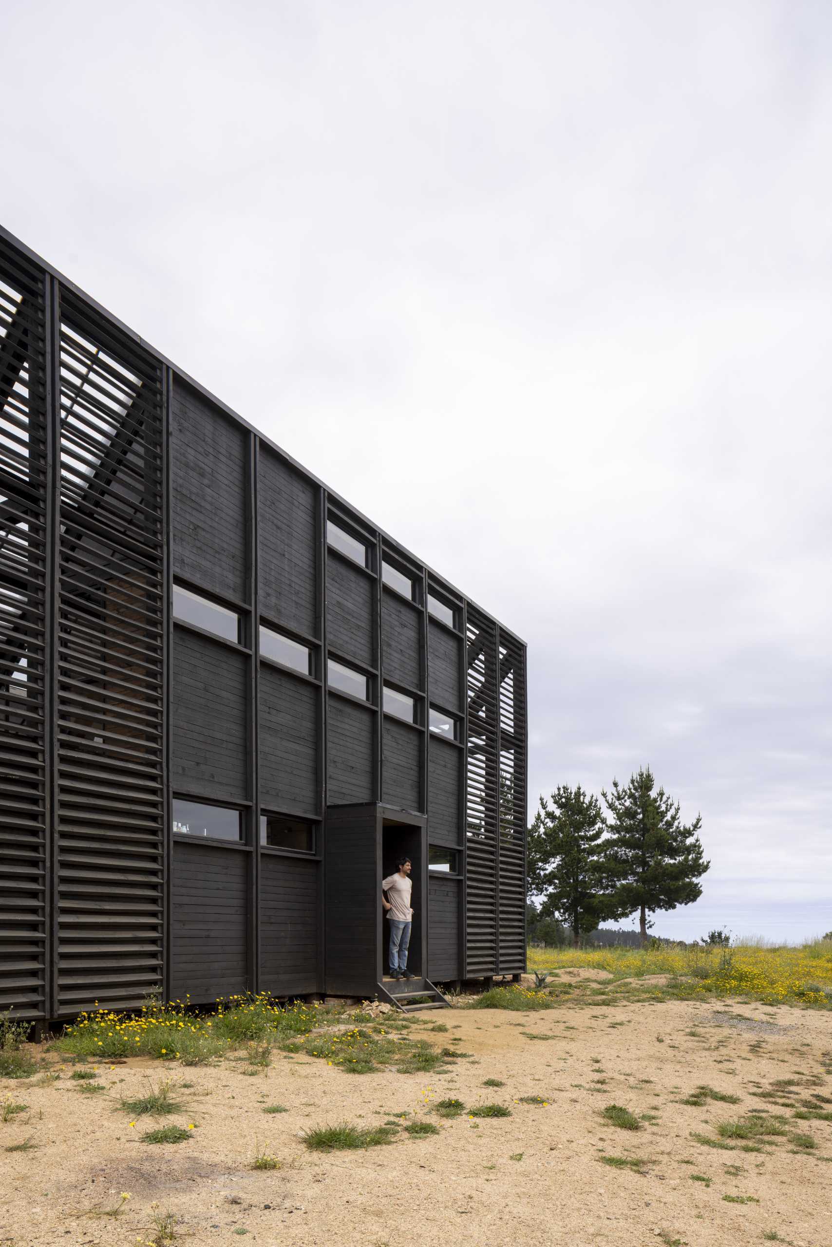 A small wedge-shaped home with a black exterior that's located on the windy beach of Matanzas, Chile.