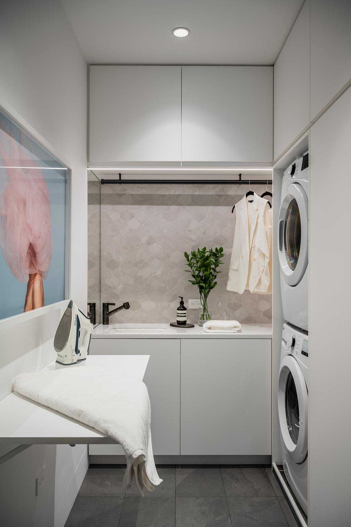 A modern laundry room with stretched-hex porcelain tile, plenty of storage, hidden lighting, and a fold-out table.