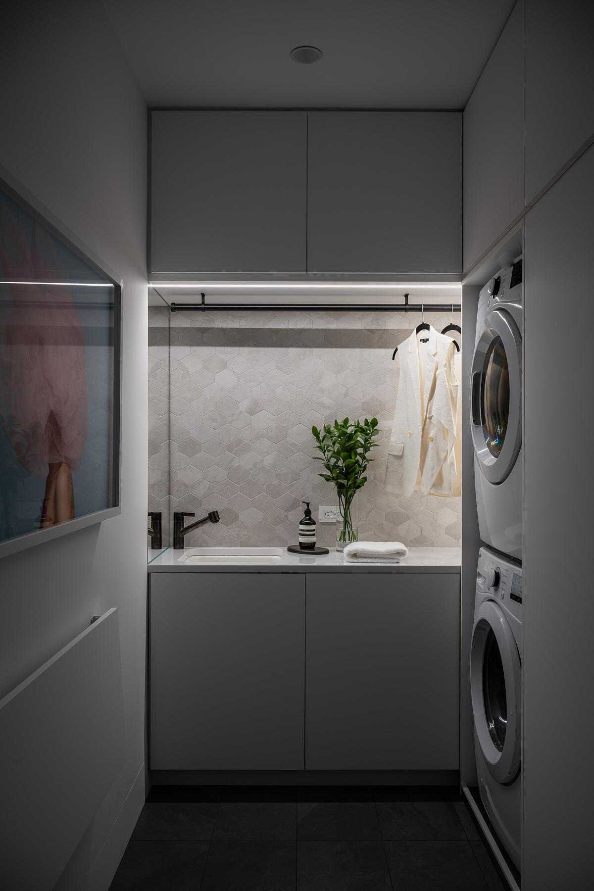 A modern laundry room with stretched-hex porcelain tile, plenty of storage, hidden lighting, and a fold-out table.