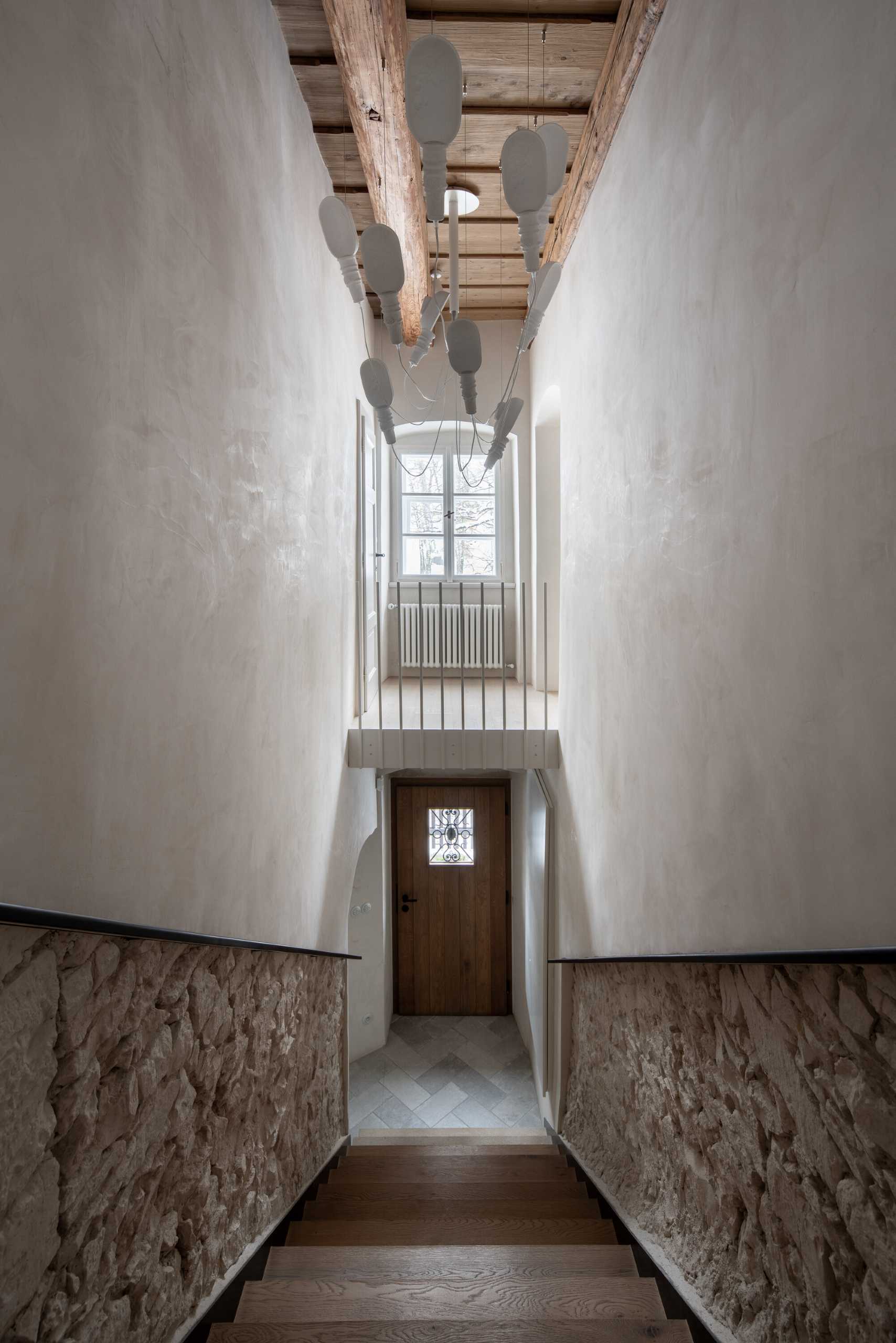 A wood staircase leads from the street entrance up to the front door, with the stone walls and exposed wood ceiling providing a glimpse of the details to come.