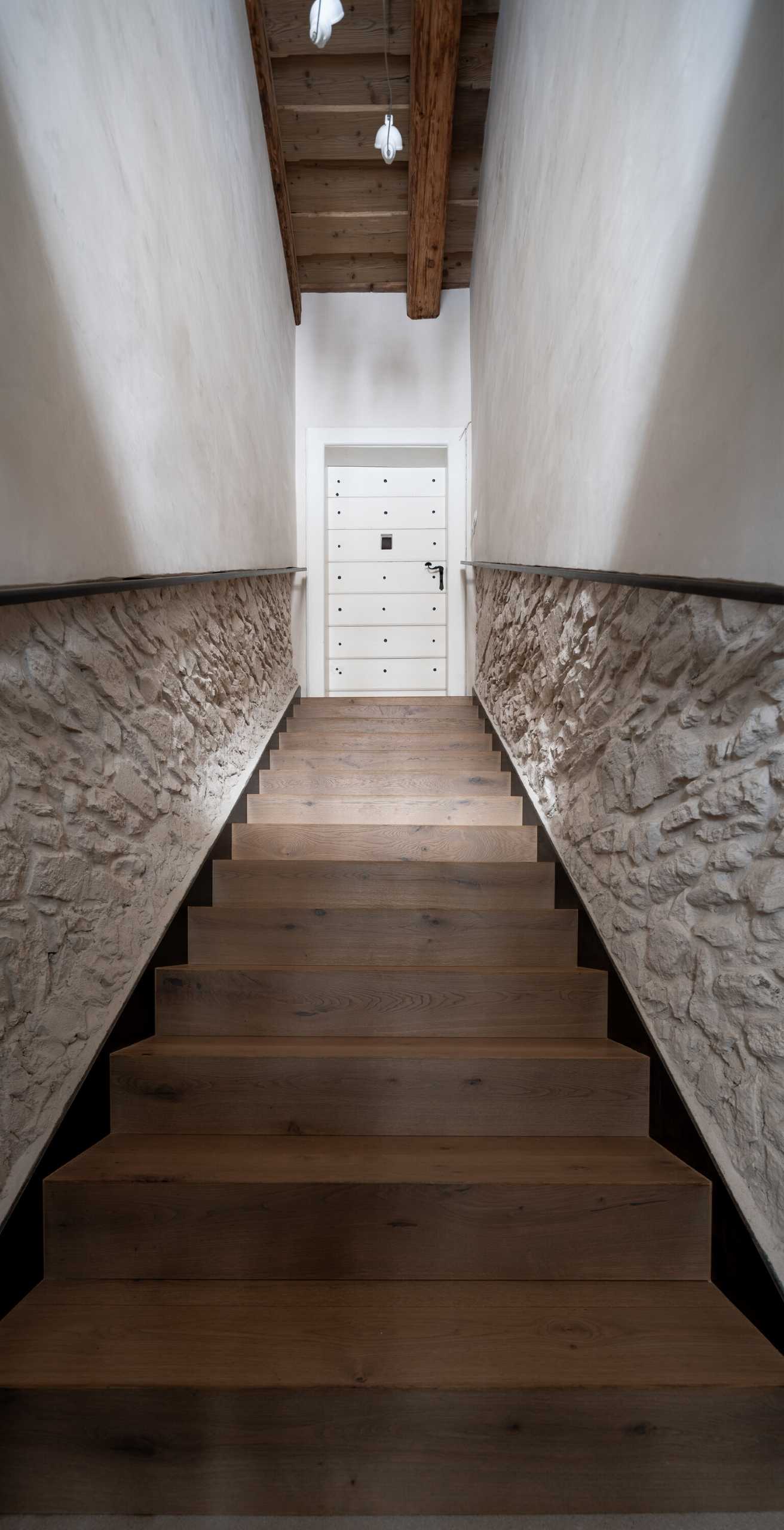 A wood staircase leads from the street entrance up to the front door, with the stone walls and exposed wood ceiling providing a glimpse of the details to come.