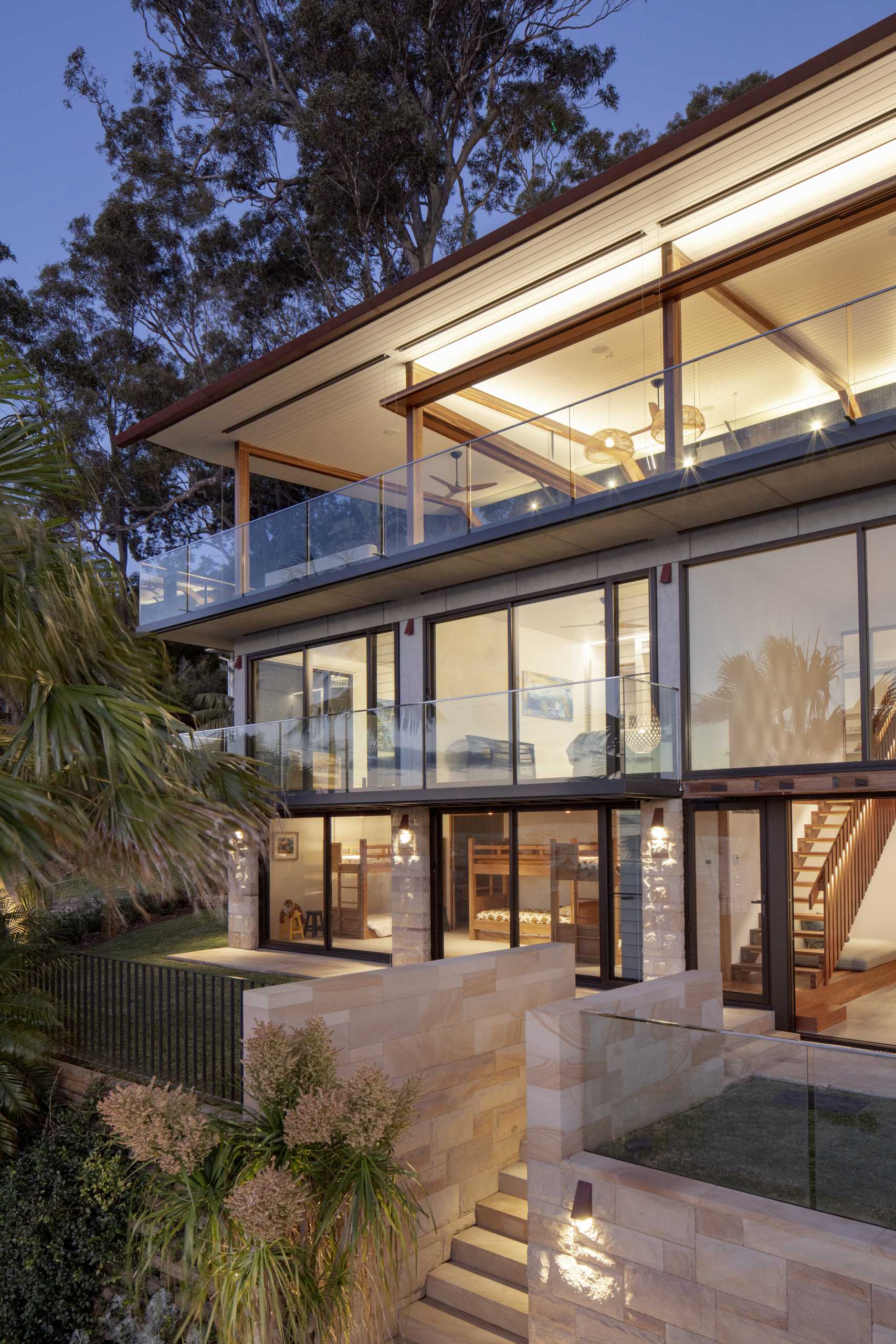 A modern waterfront home features a lightweight floating roof and timber stacking doors that slide away to open the living areas completely to the external terraces and verandah.