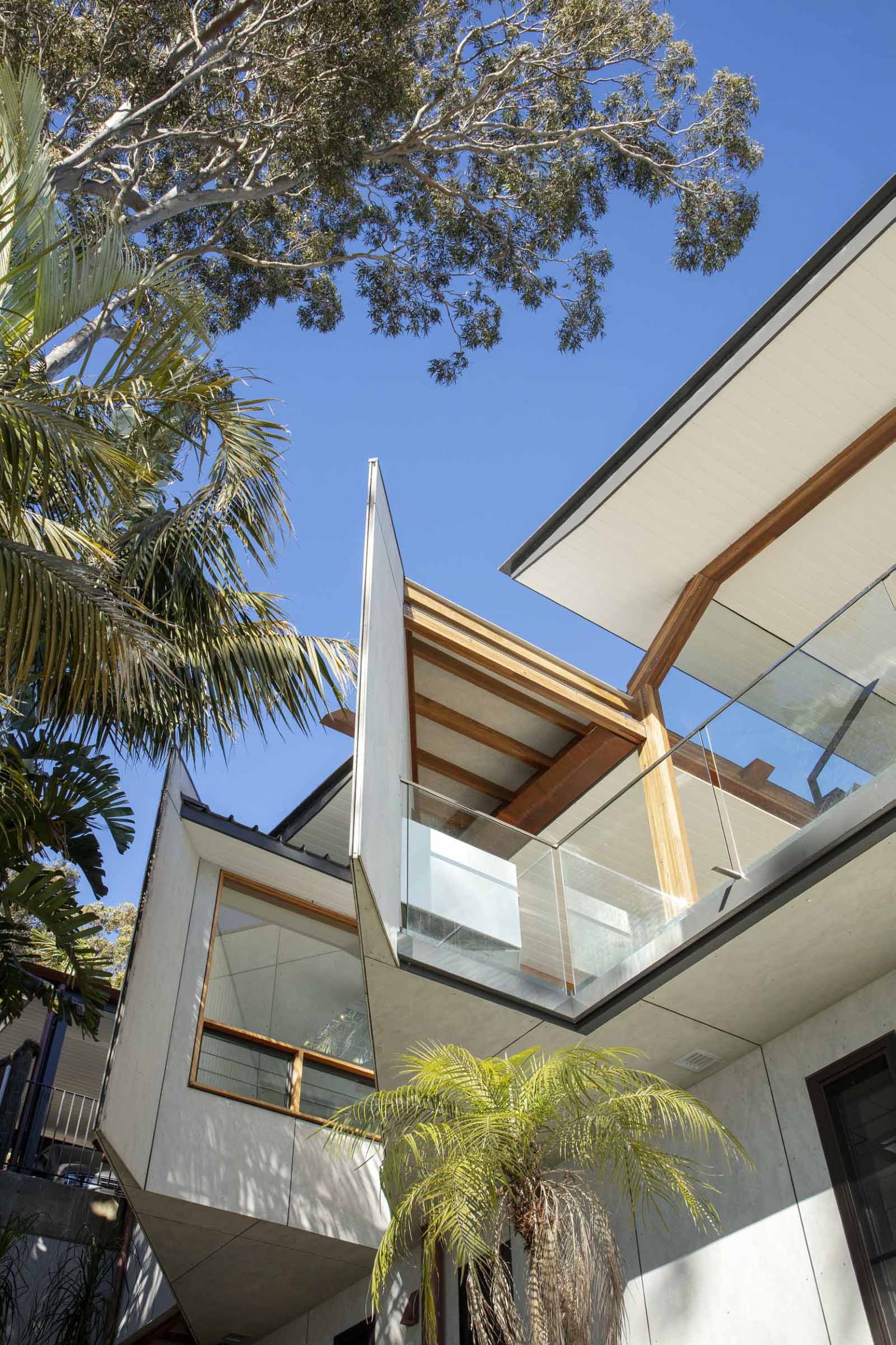 A modern waterfront home features a lightweight floating roof and timber stacking doors that slide away to open the living areas completely to the external terraces and verandah.