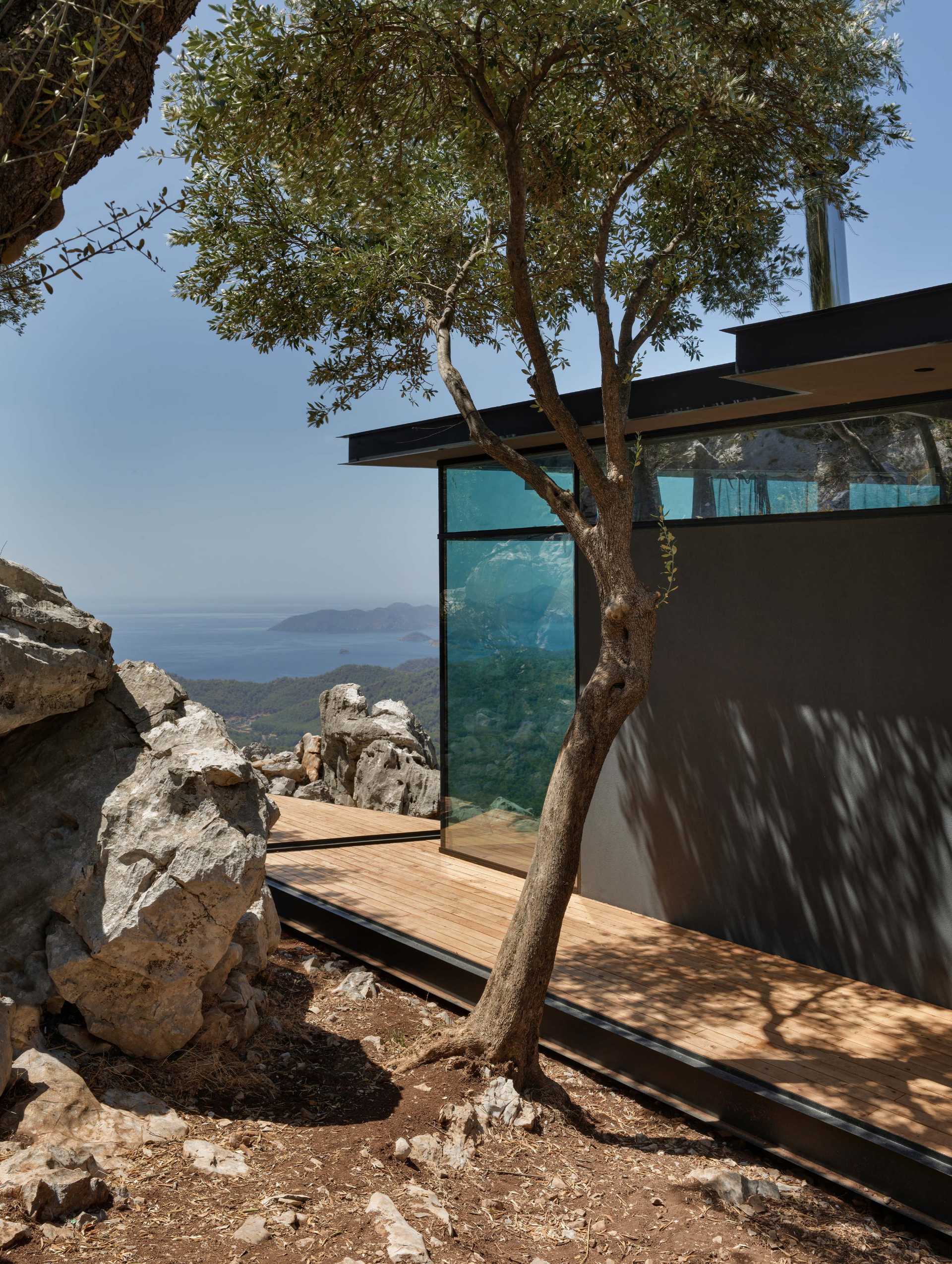 A small one-bedroom cabin with an open plan interior, is made from steel construction and a glass facade.